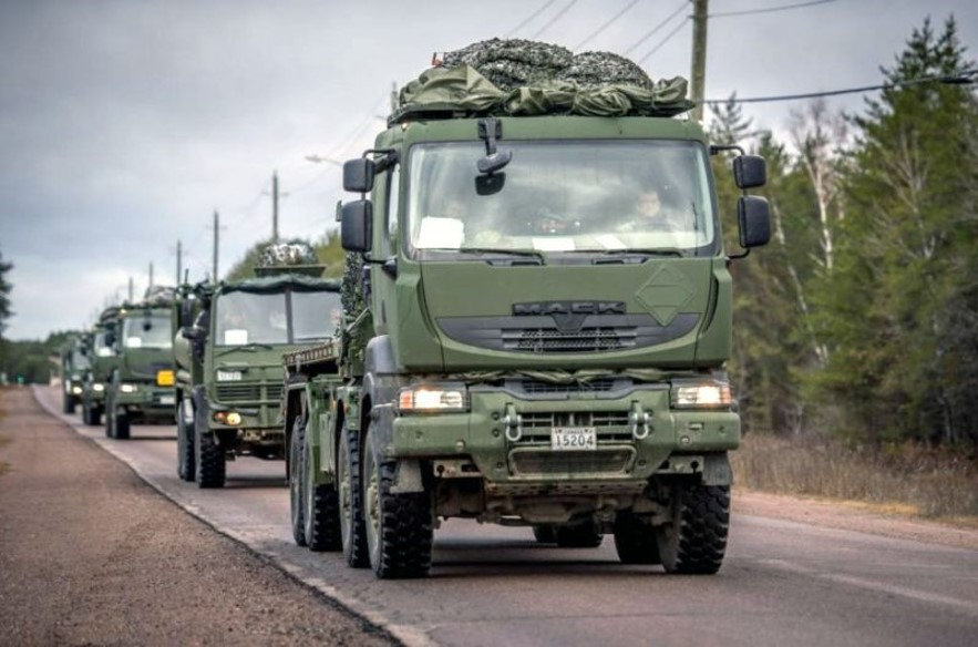 A line of green trucks driving on a road.